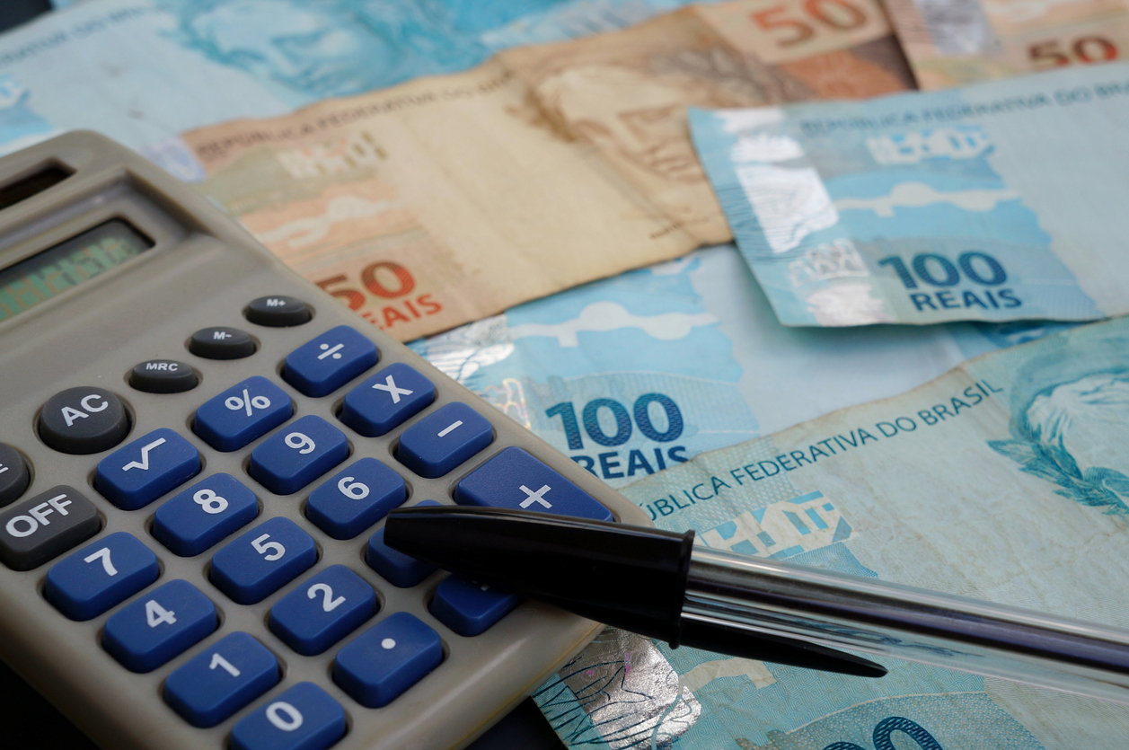 Finance Concept - Calculator, Brazilian Money and Pen on black background.