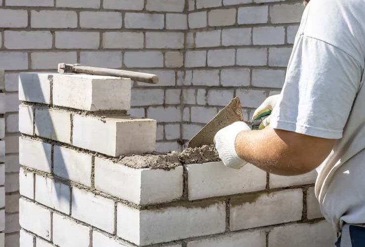 Homem com camisa branca construindo um muro de arrimo